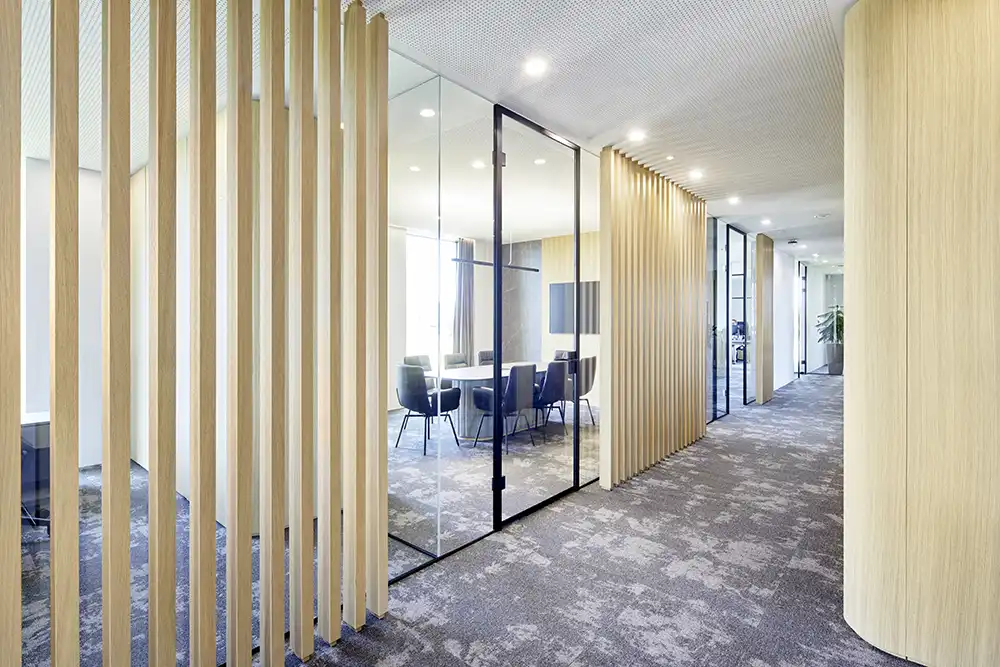 Moderner Flurbereich bei TRUST Personal mit eleganten Holzlamellen, Glasabtrennungen und Blick in einen Besprechungsraum.