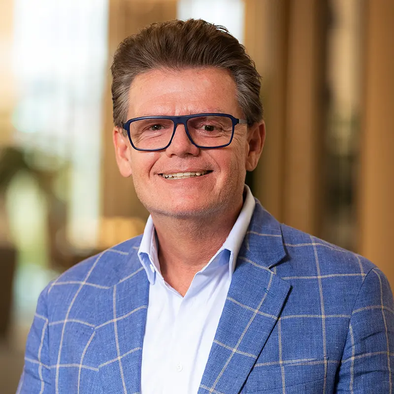 Porträtaufnahme von Geschäftsführer Roman im blauen Sakko mit Brille.