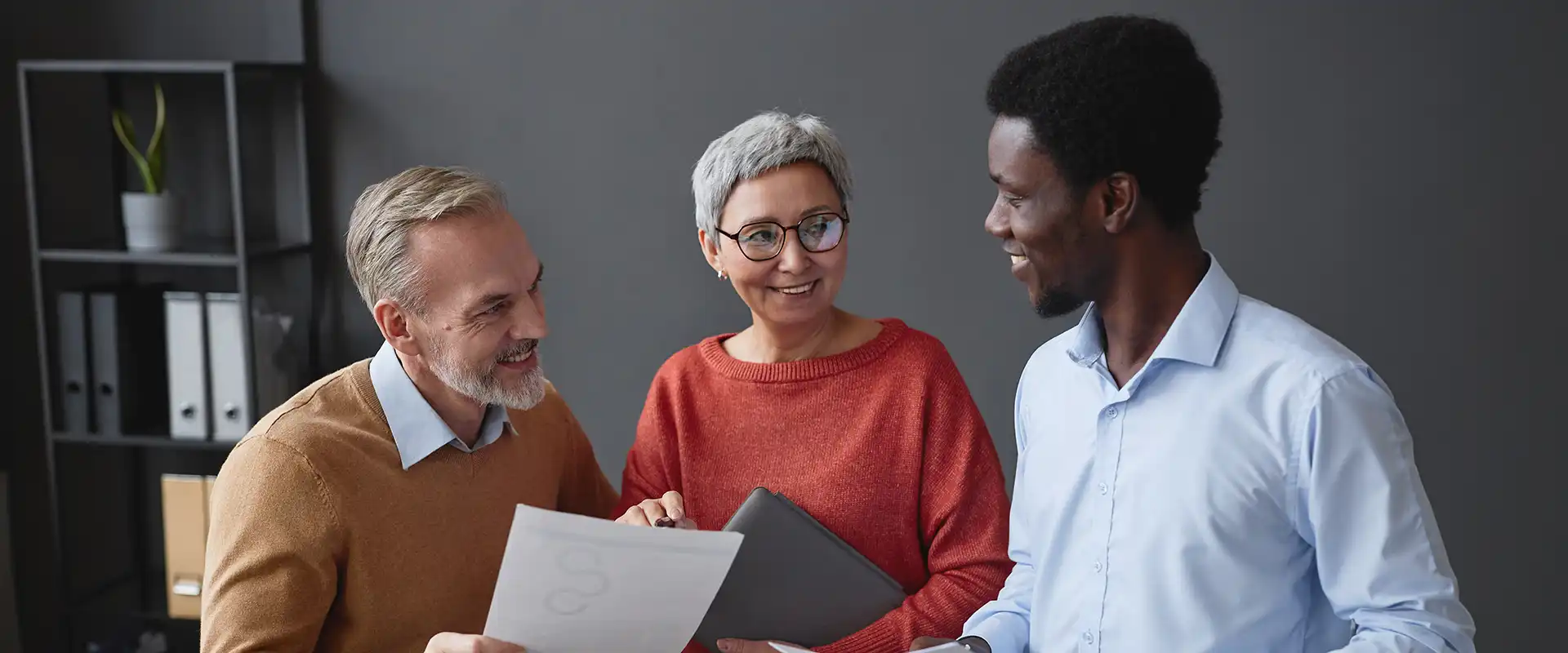 Drei Kolleginnen und Kollegen im professionellen Beratungsgespräch bei der gemeinsamen Durchsicht von Dokumenten im Büro.