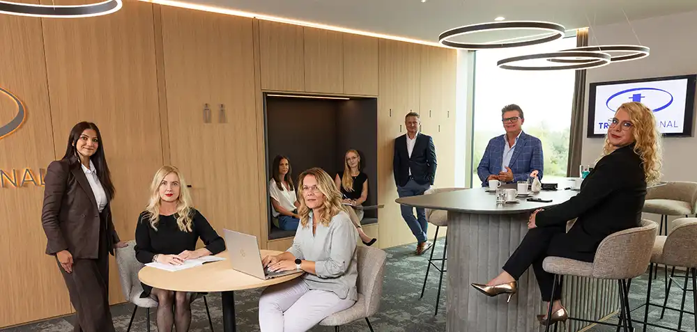 Das gesamte Team von TRUST Personal verteilt im modernen Besprechungs- und Loungebereich des Büros.