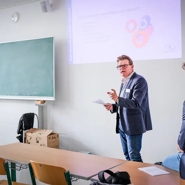 Herr Mag. Roman Ettinger, Geschäftsführer von TRUST Personal hält einen Vortrag über Gehaltsfaktoren im Bewerbungsprozess in einem Schulungsraum.