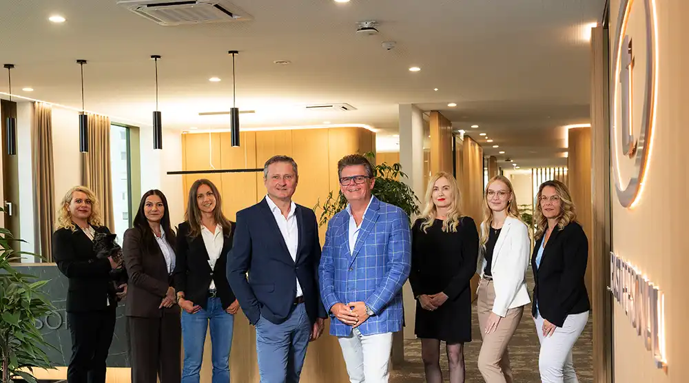 Gruppenfoto des TRUST Personal Teams im beleuchteten Empfangsbereich der Firmenzentrale.