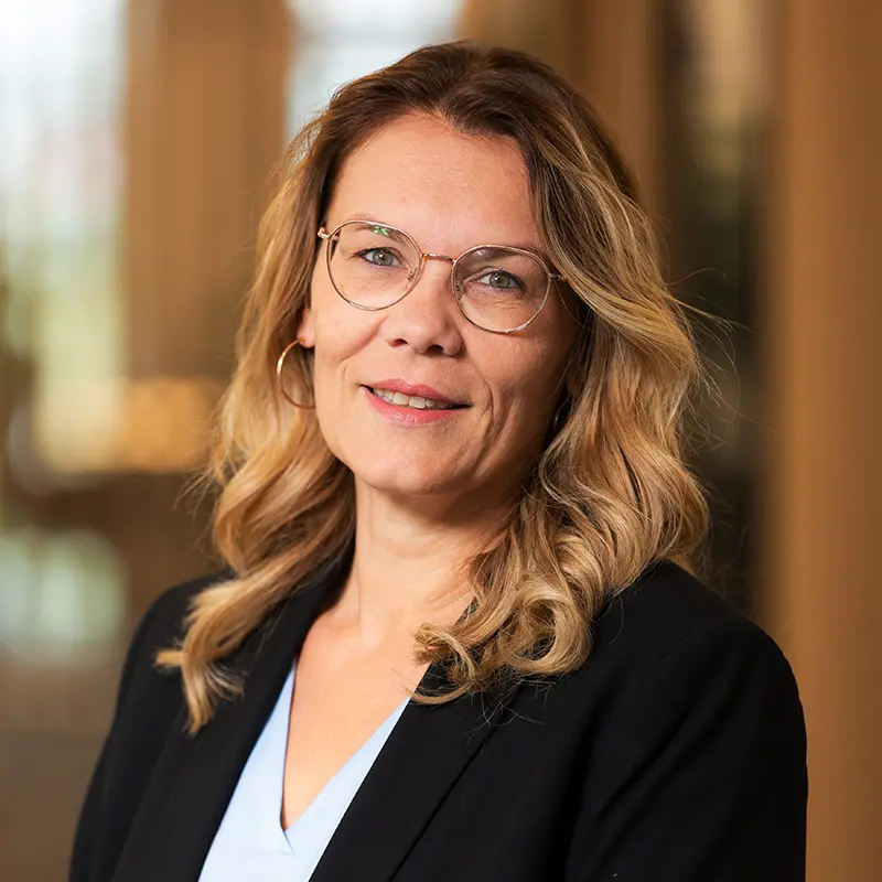 Porträtaufnahme von Tatjana, Mitarbeiterin bei TRUST Personal mit Brille und schwarzem Blazer.