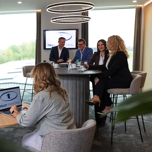 Team von TRUST Personal bei einer gemeinsamen Besprechung in der modernen Office-Lounge.