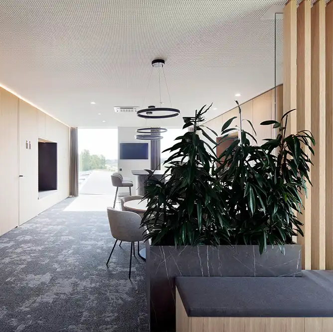 Moderner Loungebereich und Flur in den Büroräumen von TRUST Personal mit Sitzmöglichkeiten und Pflanzen.